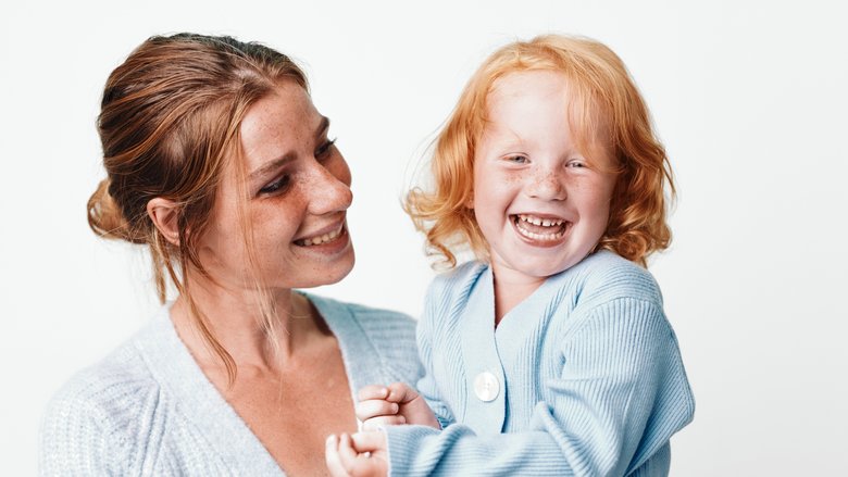 Mutter mit kleiner Tochter auf dem Arm lachen